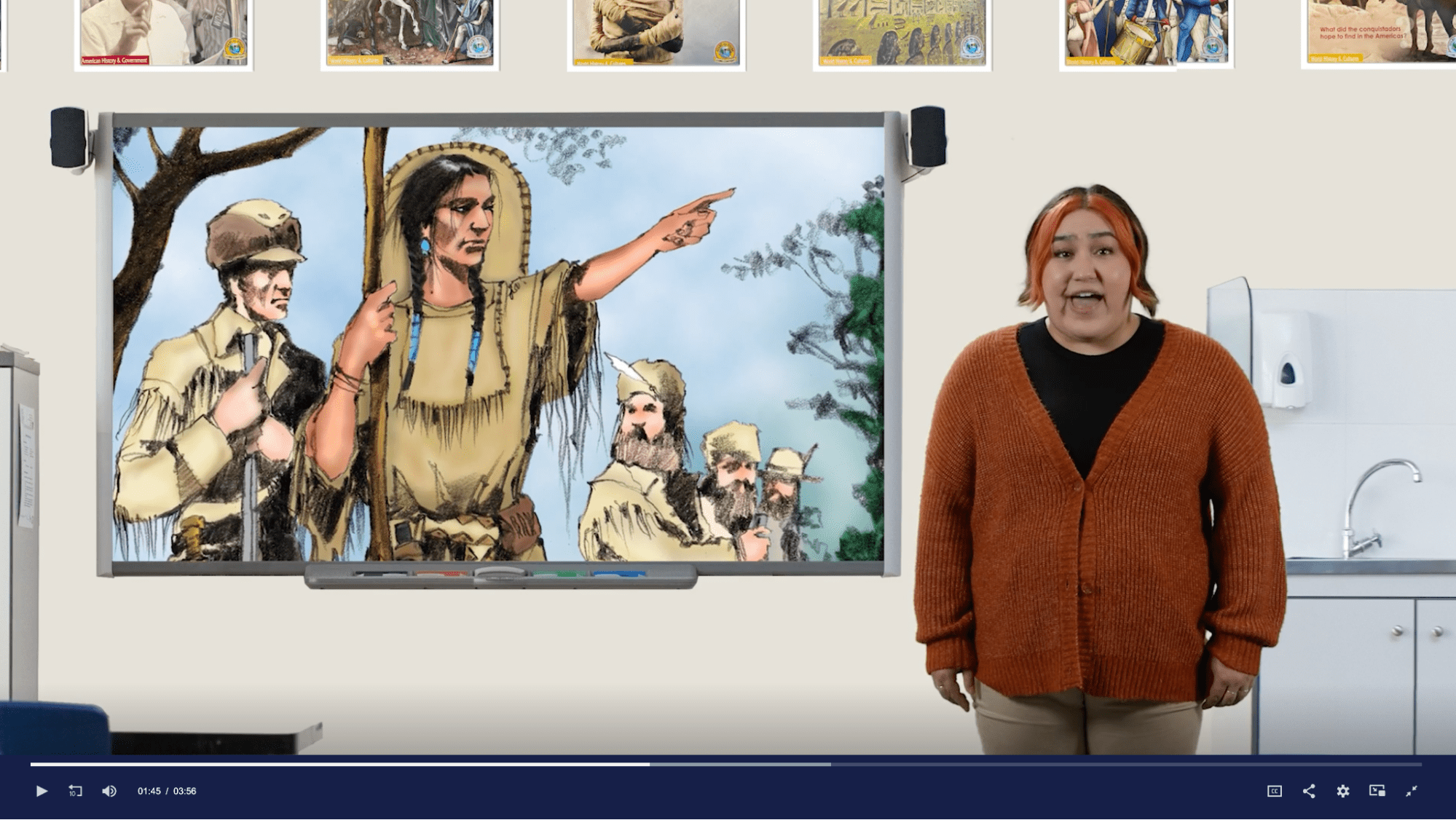 Still video clip of a student next to a smart board with an image of Sacagawea on it.