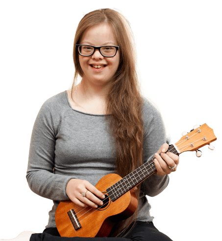 A student in a grey shirt smiles while holding a ukulele.
